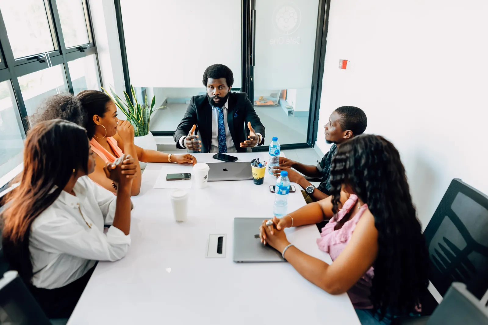 A consultant talking through a plan with two colleagues at a meeting table in a bright office