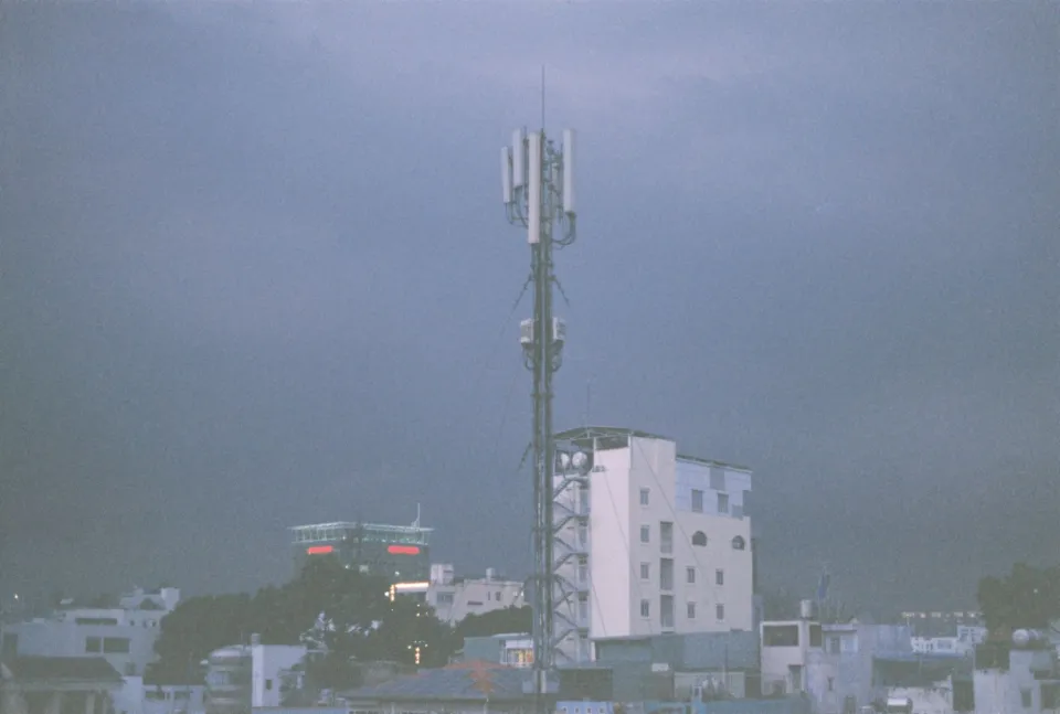 A mobile telecommunications tower standing near commercial buildings in an urban area.