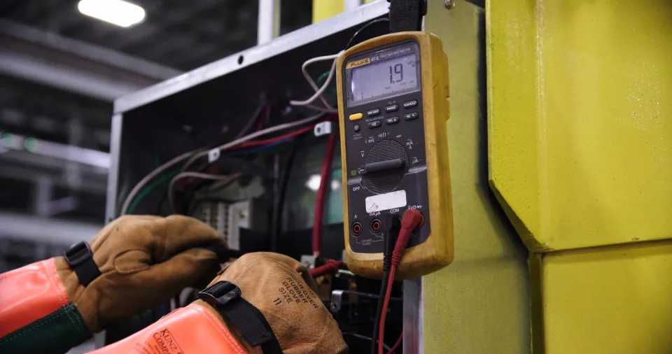 An electrical engineer checks power distribution equipment inside an industrial facility.