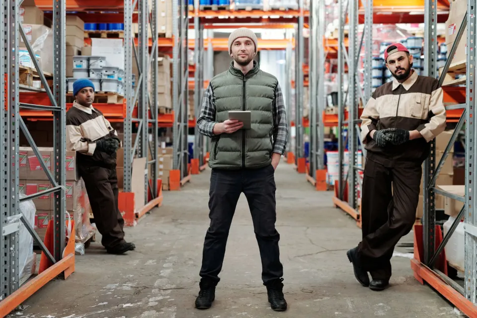 Workers inspect freight handling equipment and goods inside a logistics warehouse.