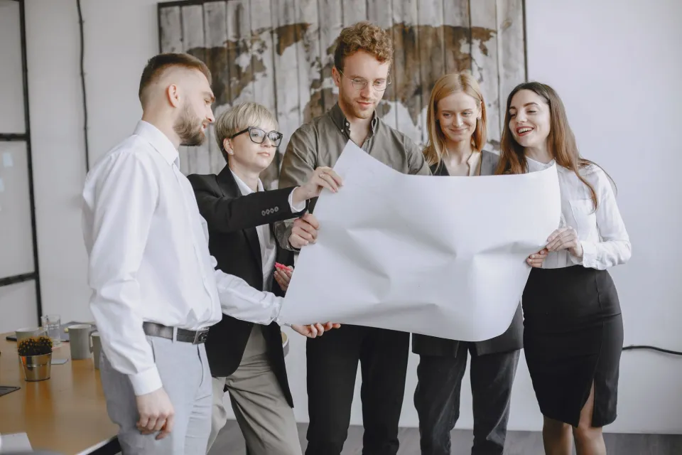 Group of professionals in an office setting analyzing project plans together.
